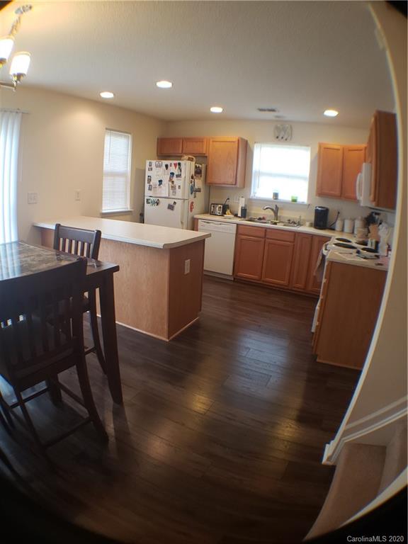 8360 Rudolph Road, Unit 2105 Charlotte, NC 28216 - Photo 8 of 14 a kitchen with stainless steel appliances kitchen island granite countertop a stove a sink a refrigerator and a dining table with wooden floor