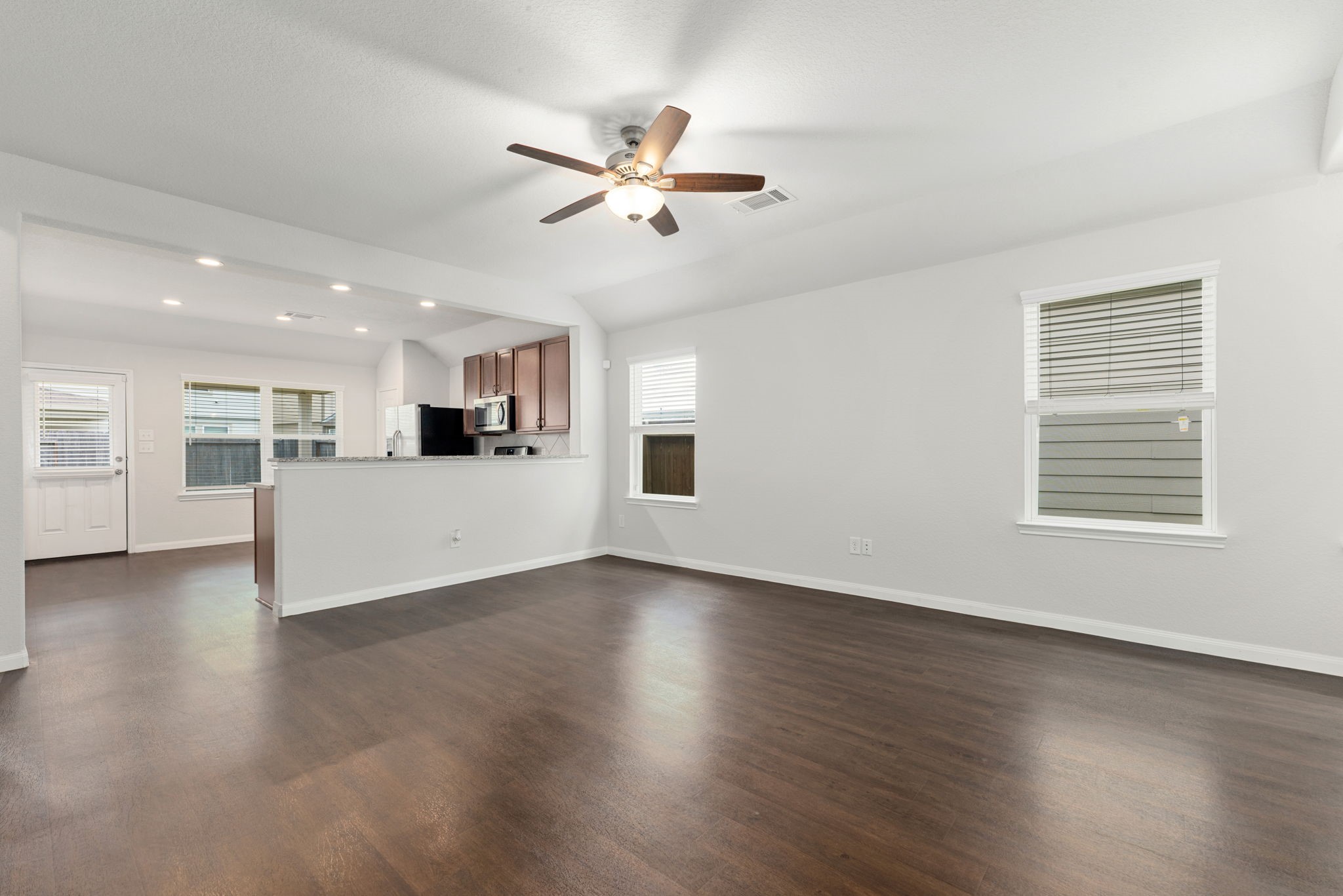 17555 Greystanes Road Humble, TX 77346 - Photo 8 of 28 a view of a livingroom with a ceiling fan wooden floor and kitchen