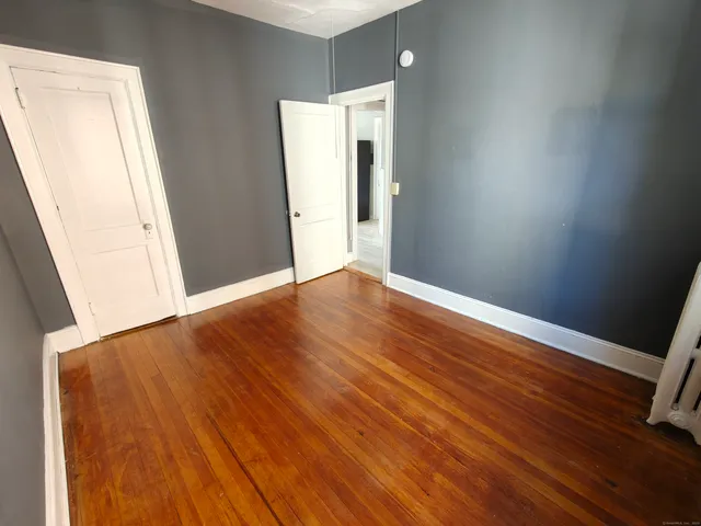 an empty room with wooden floor and a bathroom