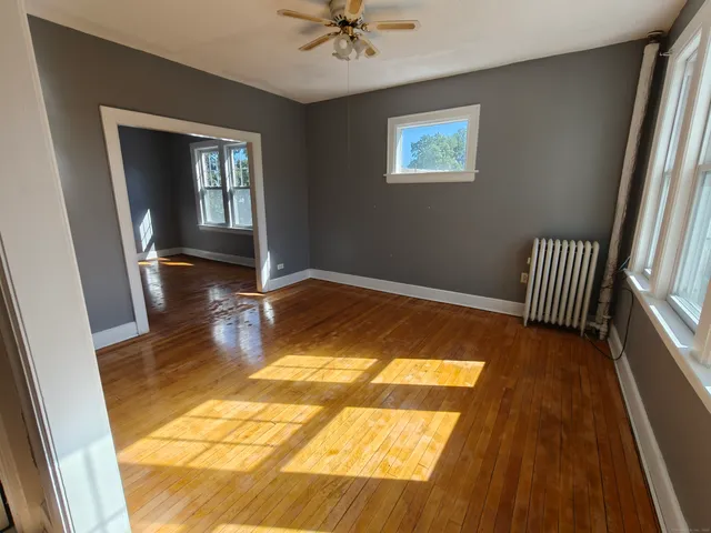 a view of an empty room with a window and wooden floor