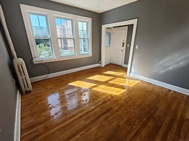 a view of an empty room with a window and wooden floor