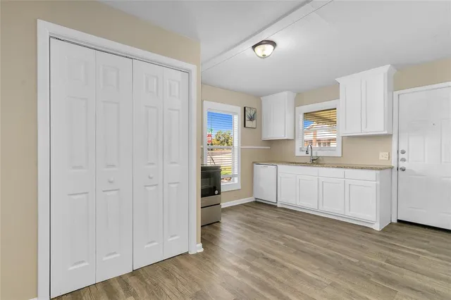 a kitchen with white cabinets and wooden floors