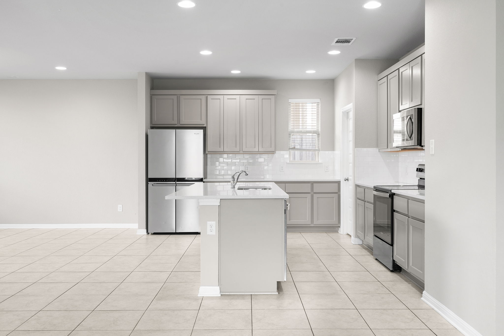313 Mclintock Road Jarrell, TX 76537 - Photo 14 of 40 A pristine open-concept kitchen features a central island, sleek appliances, and ample cabinetry for modern living.