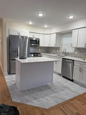 a large kitchen with stainless steel appliances granite countertop a stove a sink and a refrigerator