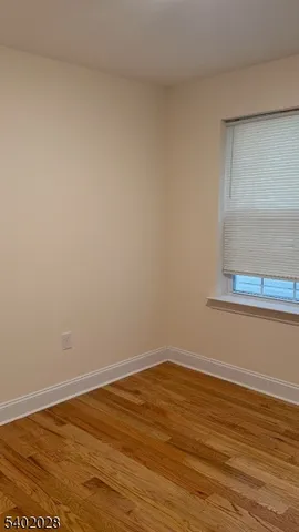 a view of an empty room with wooden floor and cabinet