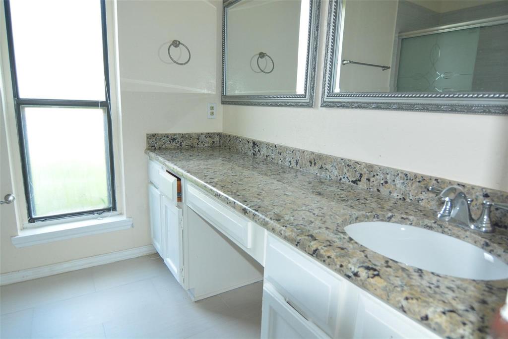 210 Apollo Road Garland, TX 75040 - Photo 19 of 23 Double vanity with integrated sinks, speckled countertop, chrome fixtures, and white cabinetry