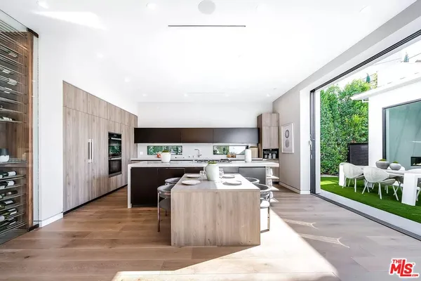 a living room with stainless steel appliances furniture a rug and a view of kitchen