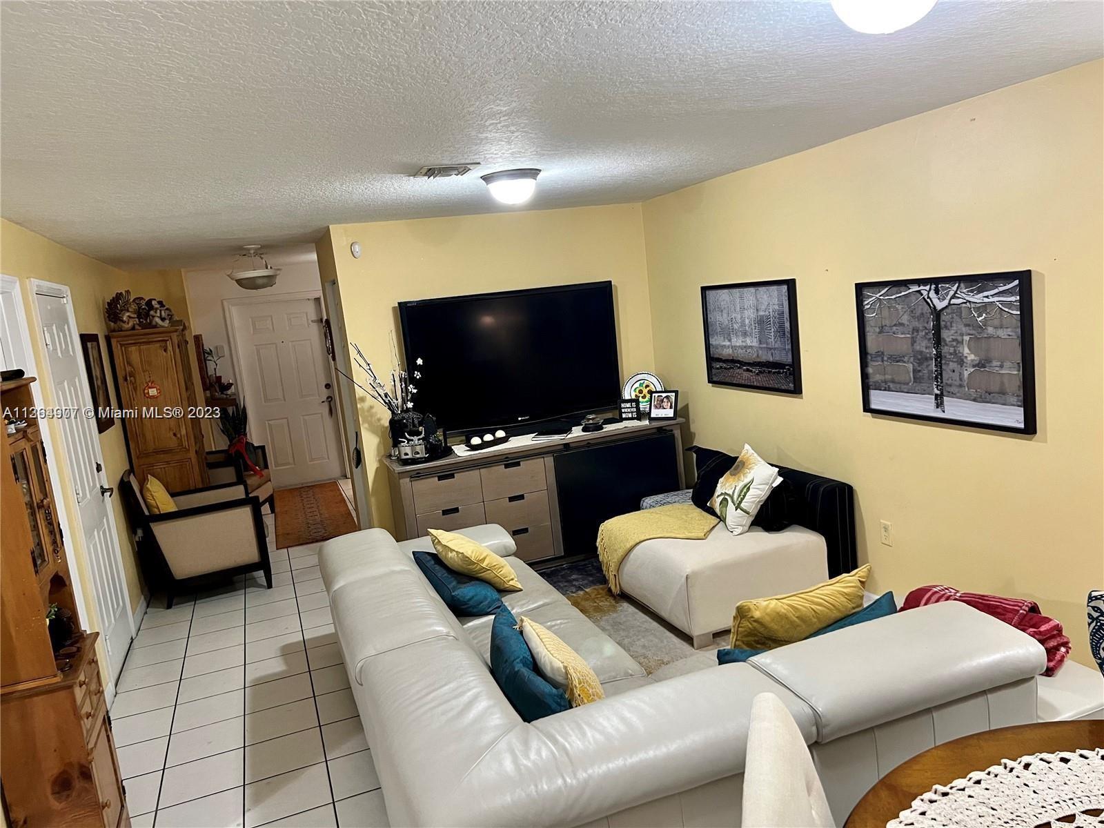 13974 Southwest 260th Street, Unit 102 Homestead, FL 33032 - Photo 4 of 16 a living room with furniture and a flat screen tv