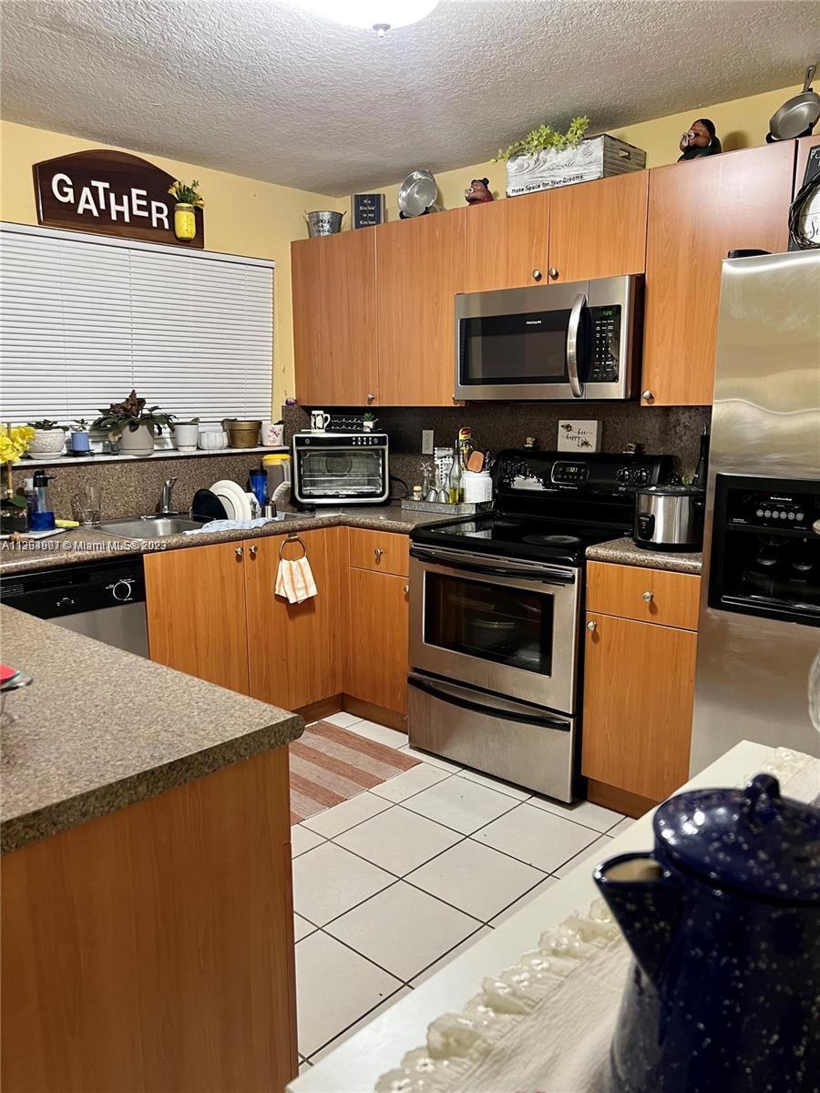 13974 Southwest 260th Street, Unit 102 Homestead, FL 33032 - Photo 6 of 16 a kitchen with stainless steel appliances a stove a sink and a microwave
