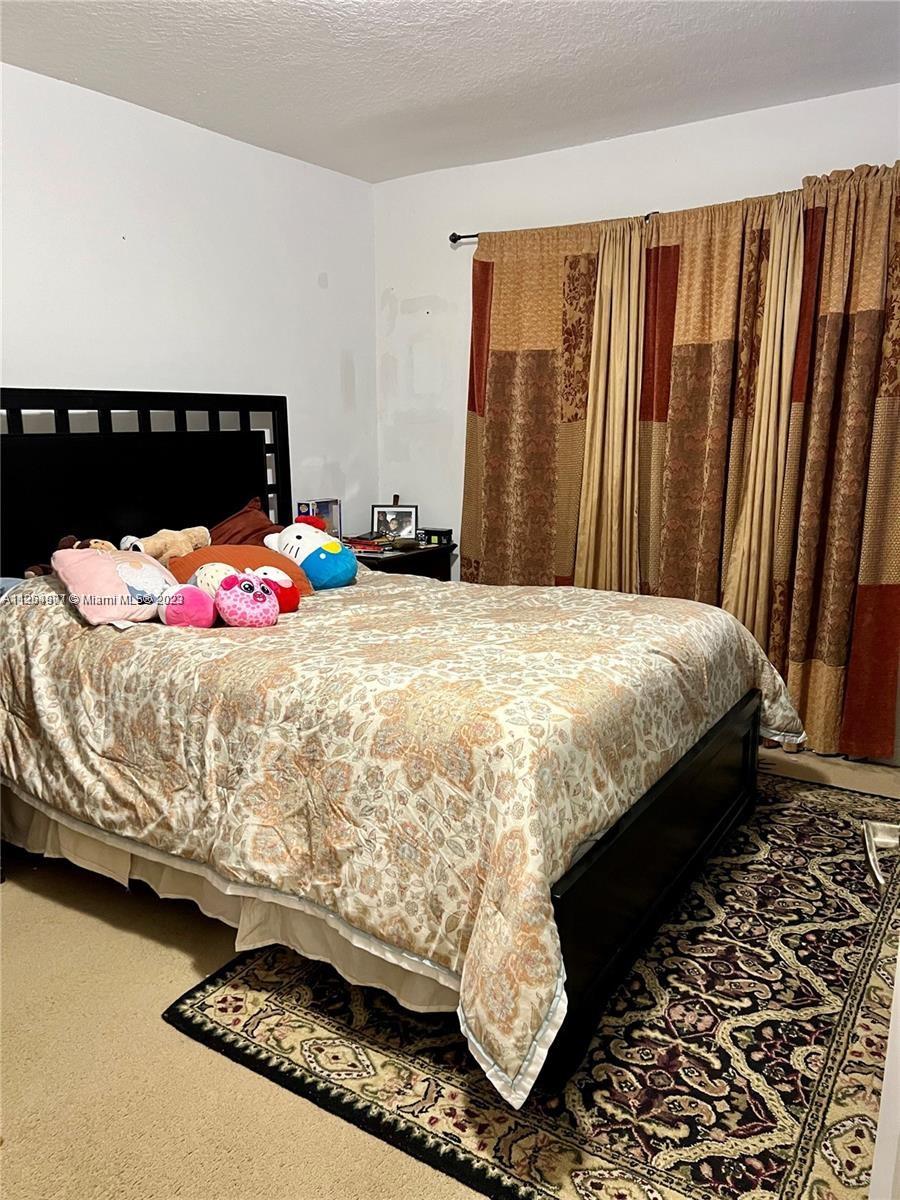 13974 Southwest 260th Street, Unit 102 Homestead, FL 33032 - Photo 7 of 16 a bed sitting in a bedroom next to a window