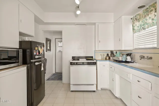 a kitchen with granite countertop white cabinets white appliances a sink and a window