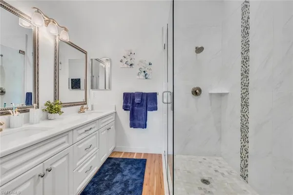 a spacious bathroom with a double vanity sink a mirror a shower and vanity
