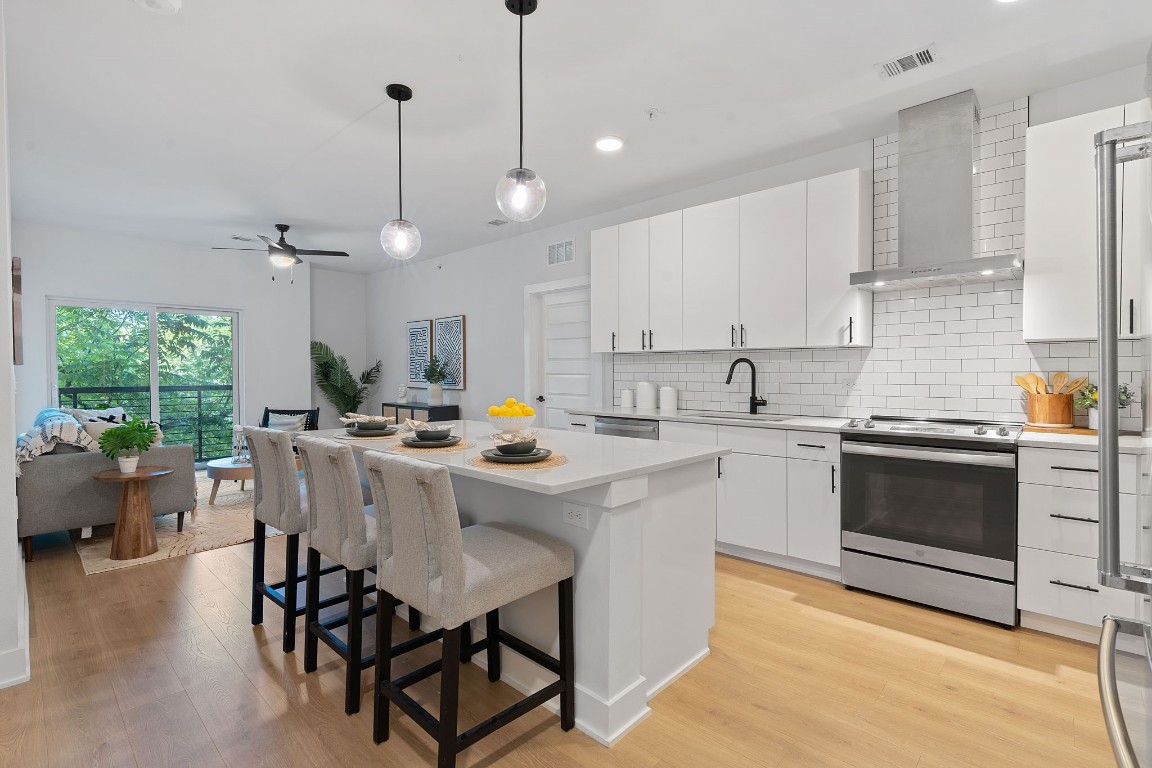 a kitchen with a stove a sink a kitchen island with a dining table and chairs