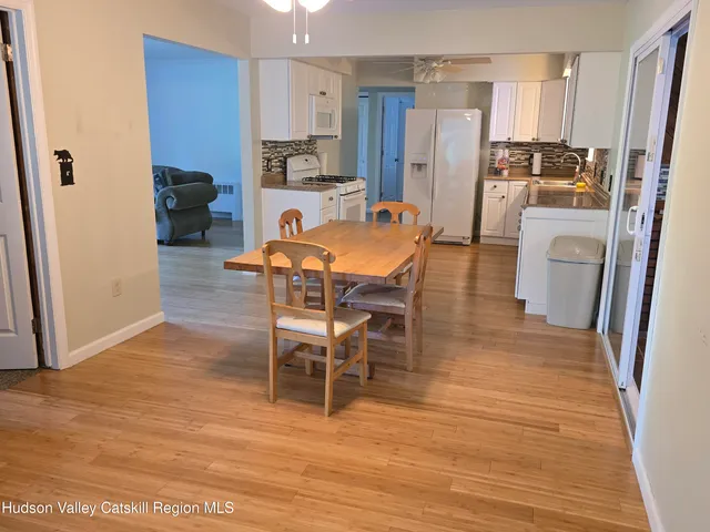 a living room with stainless steel appliances furniture wooden floor and a view of kitchen