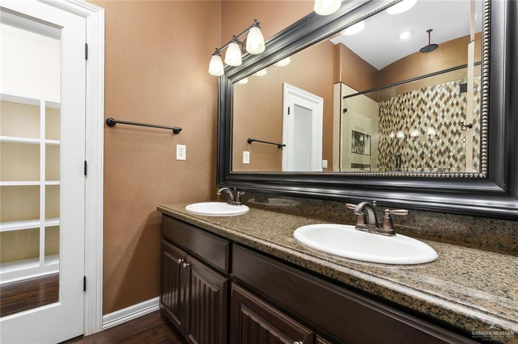 1910 West 41st Street Mission, TX 78573 - Photo 12 of 15 a bathroom with a granite countertop sink a mirror and a shower
