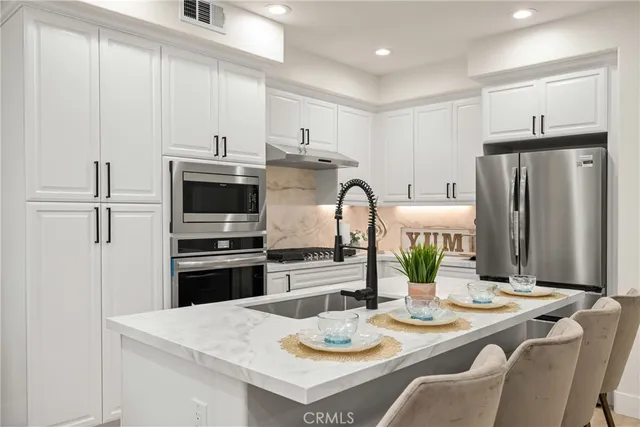 a kitchen with stainless steel appliances kitchen island granite countertop a dining table and chairs
