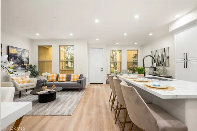 a living room with furniture kitchen view and a large window