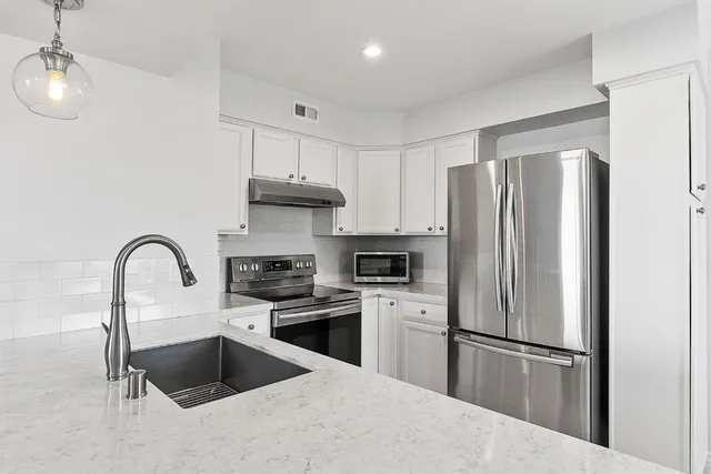 a kitchen with stainless steel appliances kitchen island a refrigerator sink and cabinets