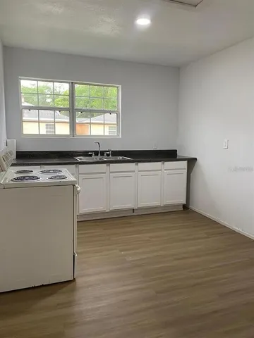 a kitchen with granite countertop a stove a sink and a microwave