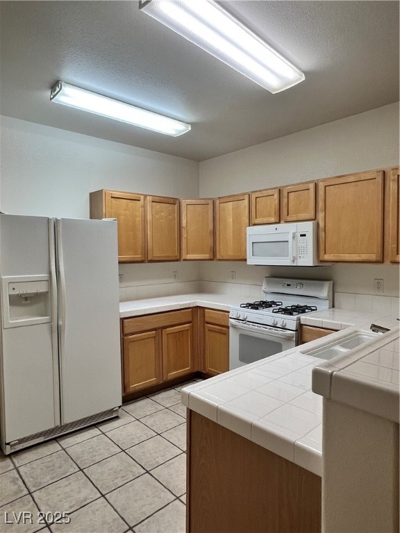 2152 Quarry Ridge Street, Unit 103 Las Vegas, NV 89117 - Photo 28 of 43 Kitchen featuring tile countertops, fridge, range, light tile patterned floors, and white microwave