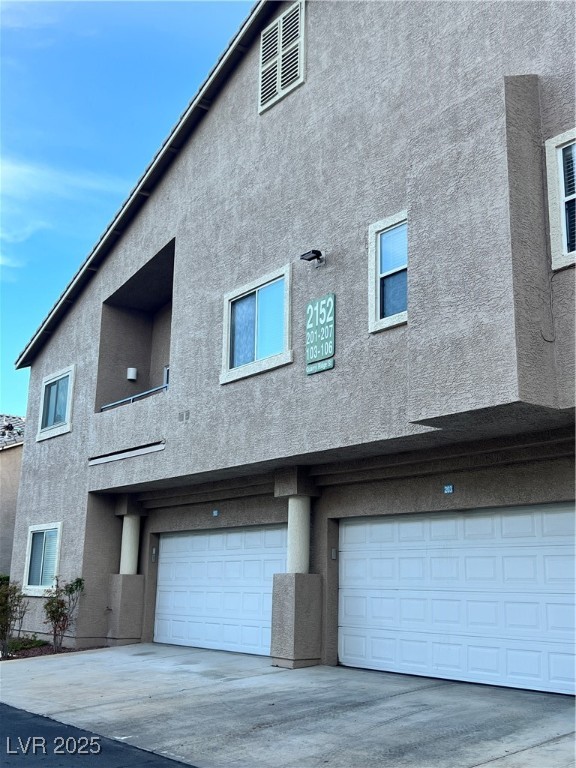 2152 Quarry Ridge Street, Unit 103 Las Vegas, NV 89117 - Photo 32 of 43 Back of house with stucco siding, an attached garage, and driveway