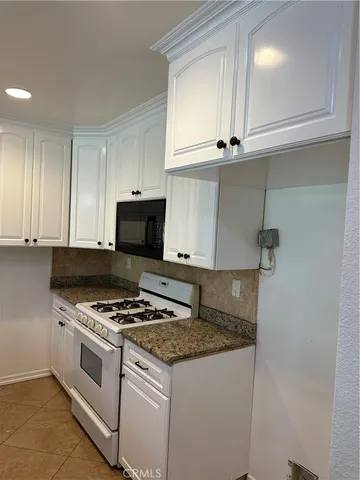 a kitchen with granite countertop a stove a sink and a microwave