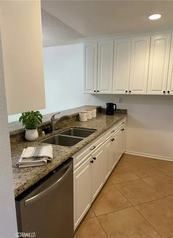 a white kitchen with granite countertop cabinets and a sink