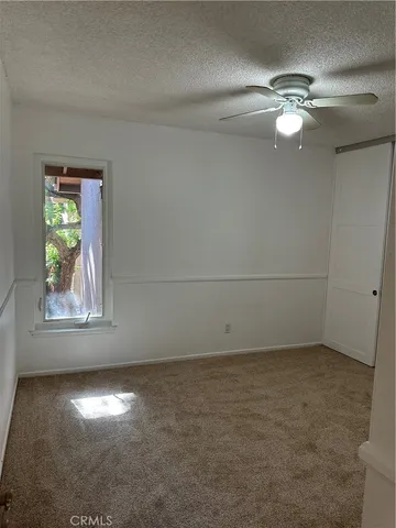 an empty room with a window and a chandelier fan