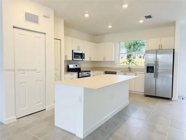 a kitchen with stainless steel appliances a refrigerator sink and microwave