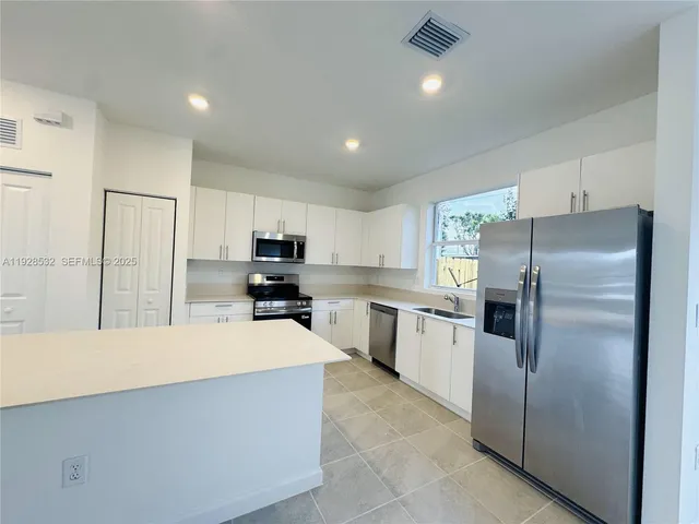 a kitchen with a refrigerator a sink and cabinets