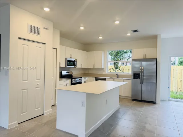 a view of kitchen with sink electronic appliances and window