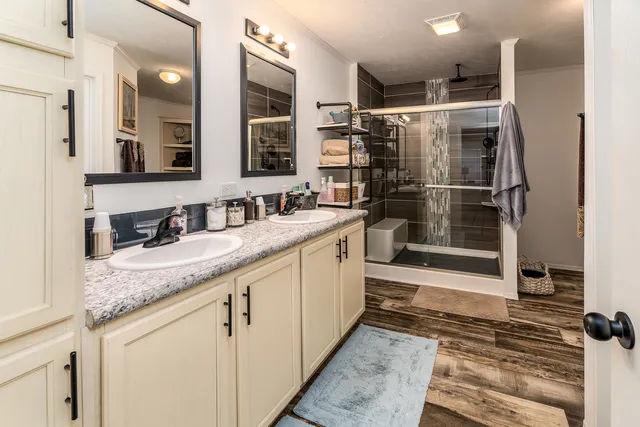 a bathroom with a granite countertop sink a mirror and shower
