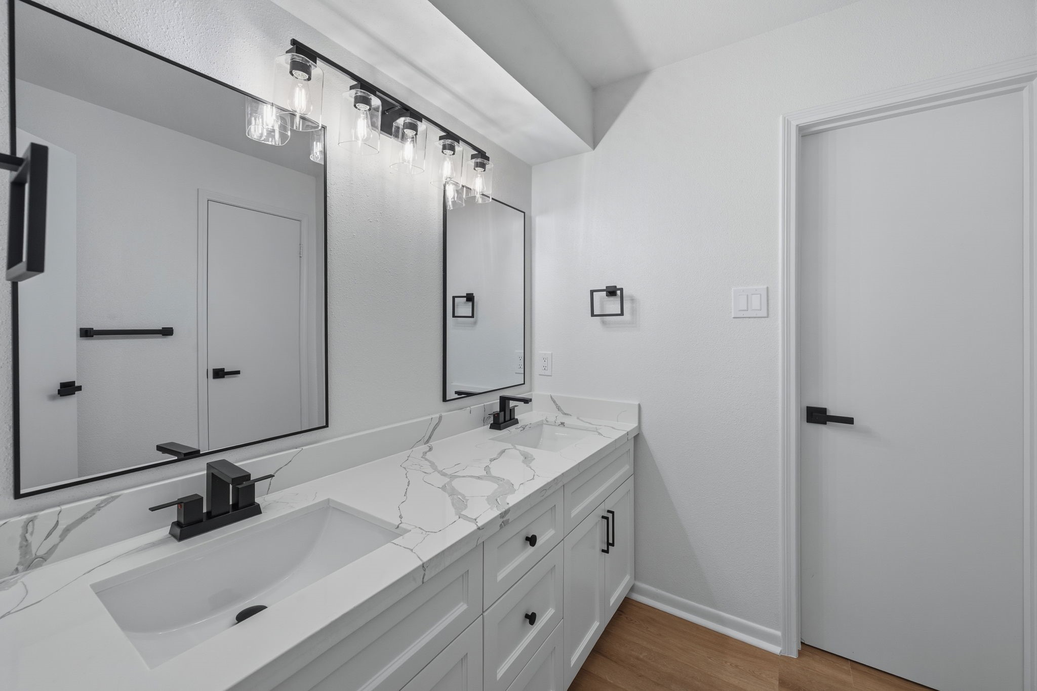 210 Ridgemont Drive Alvin, TX 77511 - Photo 17 of 27 This bathroom features a modern double vanity with a sleek marble countertop, stylish black fixtures, and large mirrors, complemented by bright lighting and a clean, minimalist design.
