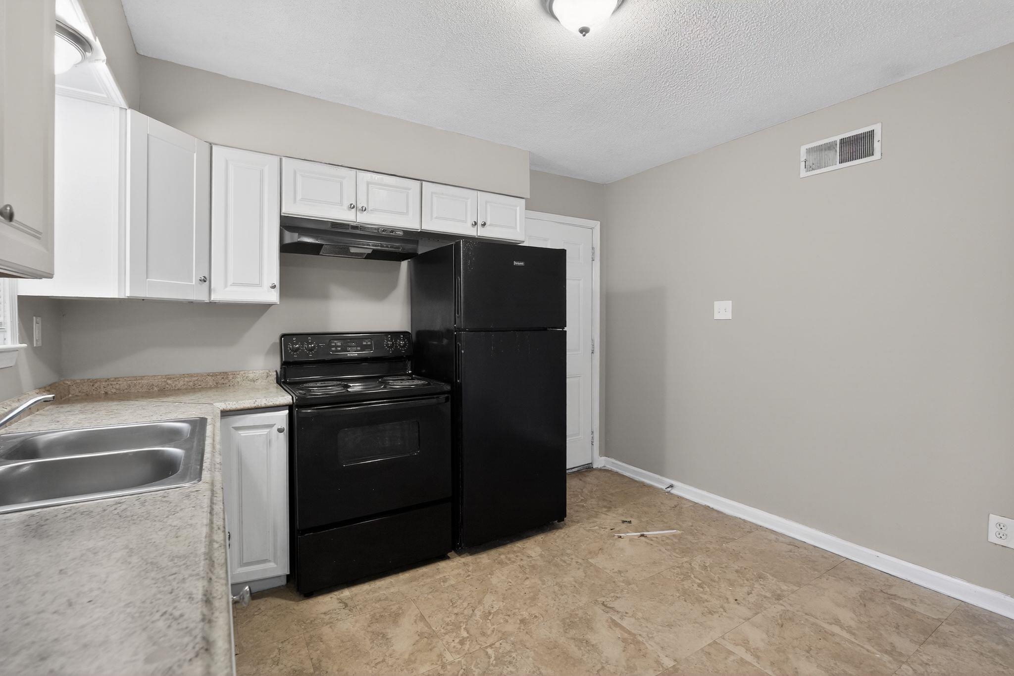 4094 Double Tree Street Memphis, TN 38109 - Photo 22 of 31 Kitchen with black appliances, white cabinets, light countertops, and a textured ceiling
