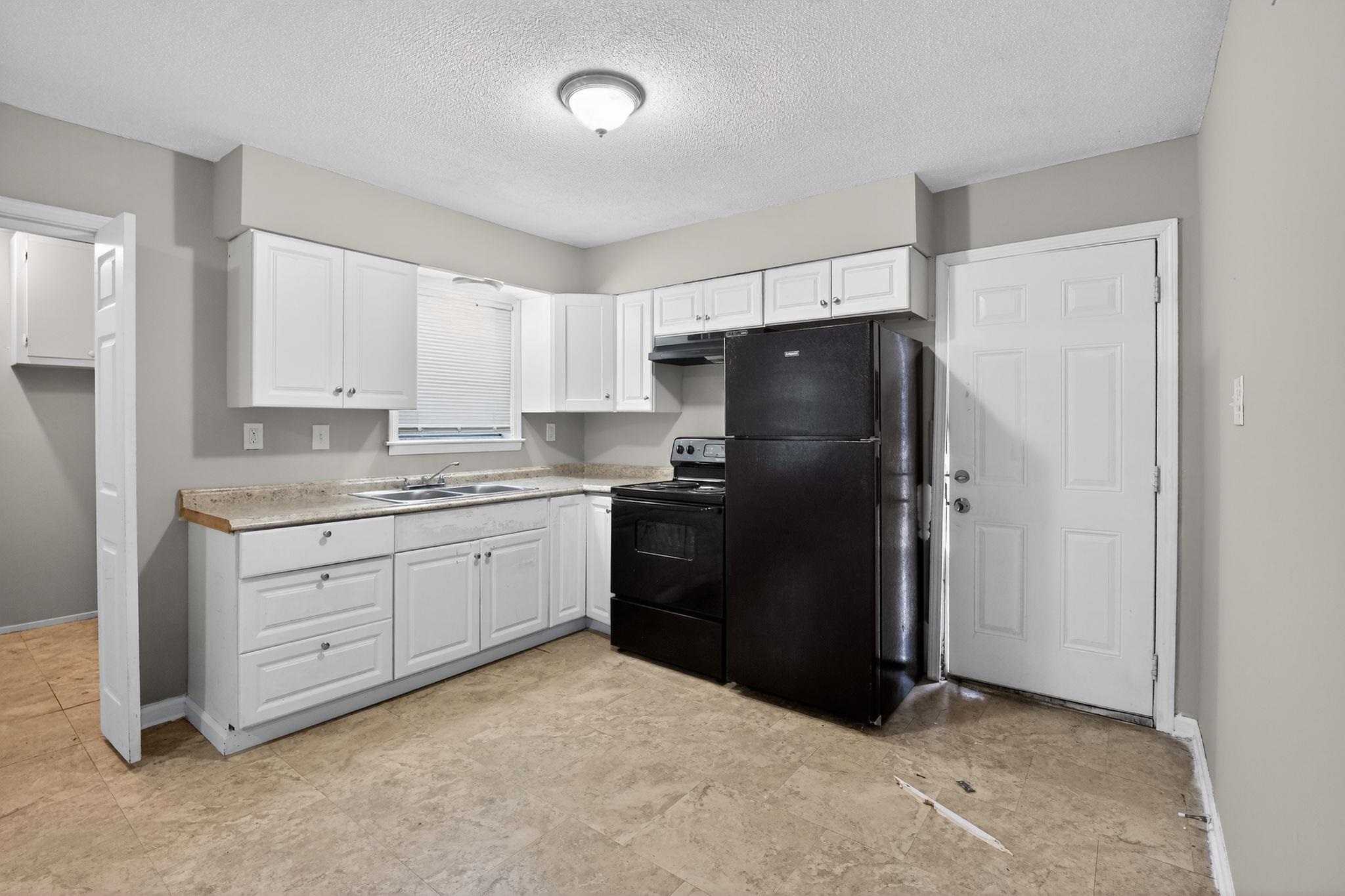 4094 Double Tree Street Memphis, TN 38109 - Photo 23 of 31 Kitchen featuring black appliances, light countertops, white cabinets, and a textured ceiling