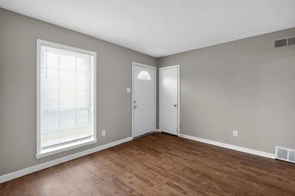 an empty room with wooden floor and windows
