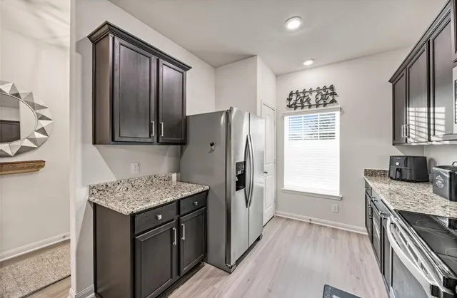 a kitchen with stainless steel appliances granite countertop refrigerator stove top oven and cabinets