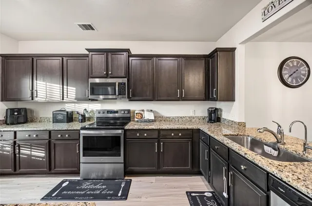 a kitchen with stainless steel appliances granite countertop a sink stove and refrigerator
