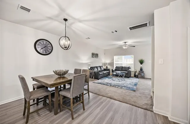 a view of a dining room and livingroom with furniture wooden floor and a chandelier