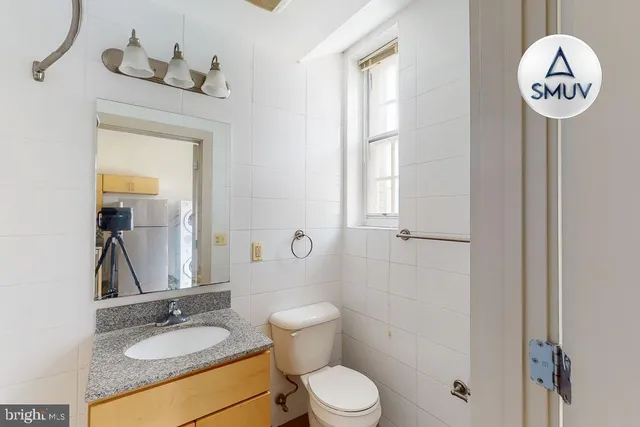 a bathroom with a toilet a sink a mirror and a window