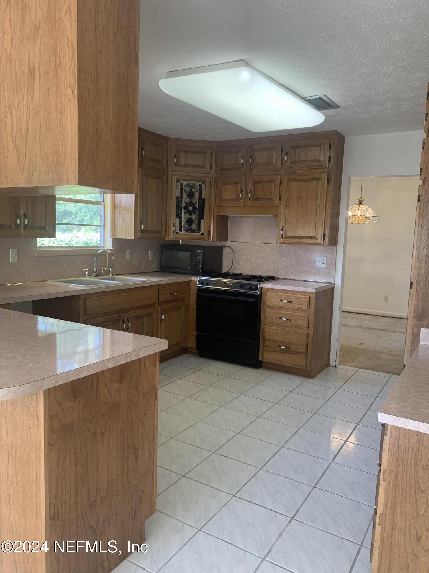 10558 Tulsa Road Jacksonville, FL 32218 - Photo 17 of 24 a kitchen with stainless steel appliances a stove a sink and a microwave