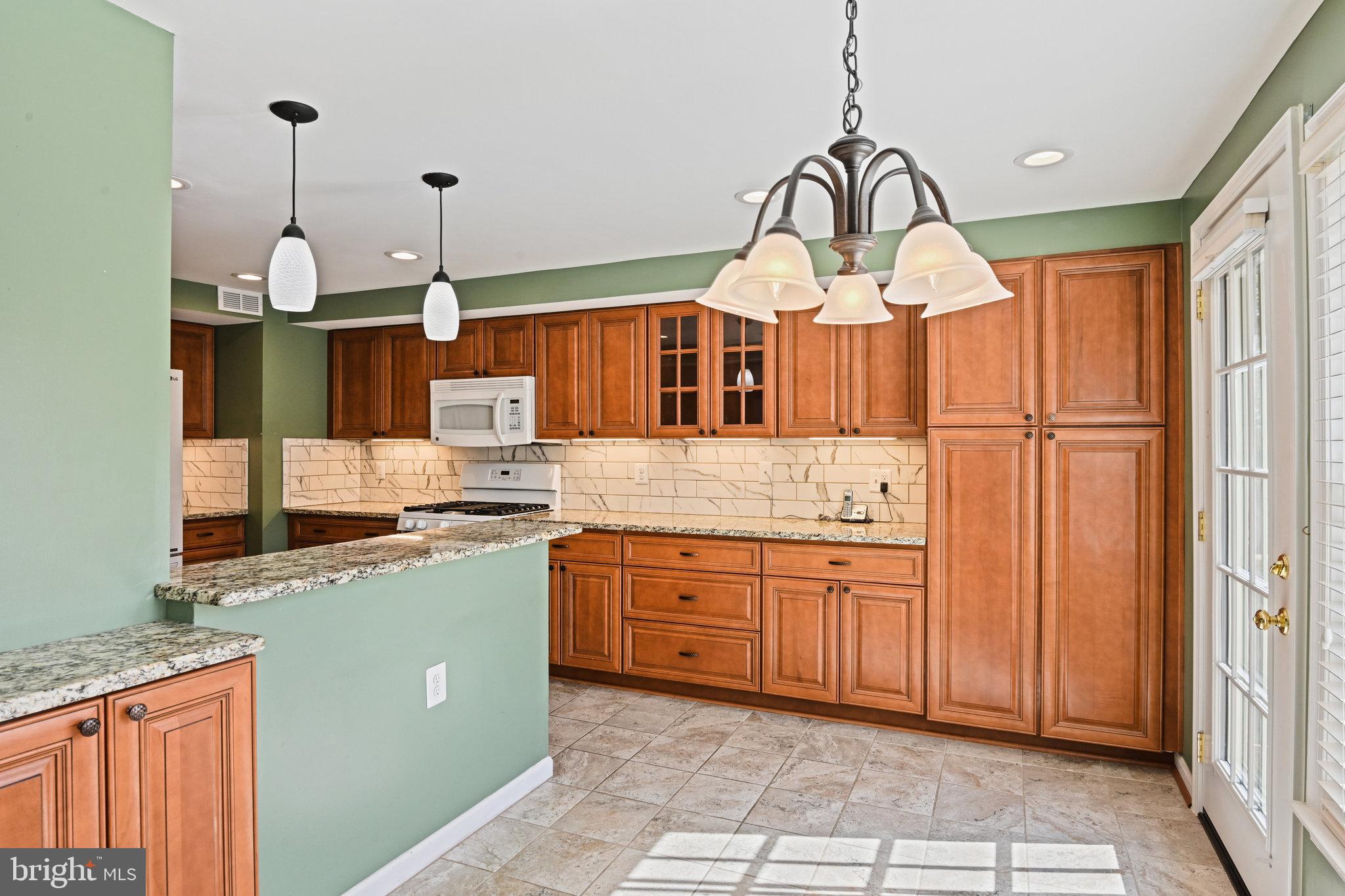 21174 Wildflower Square Ashburn, VA 20147 - Photo 11 of 30 a kitchen with granite countertop a sink a stove and a wooden floor