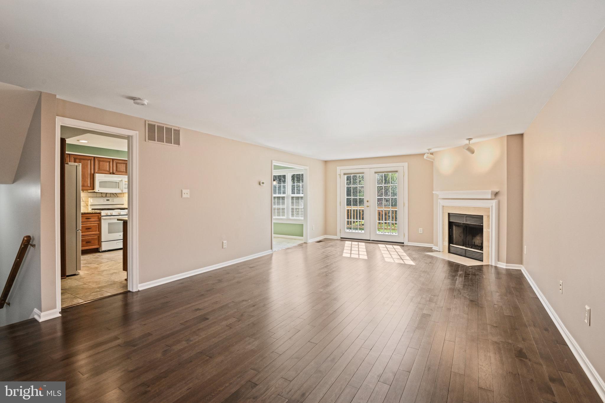 21174 Wildflower Square Ashburn, VA 20147 - Photo 5 of 30 an empty room with wooden floor fireplace and windows