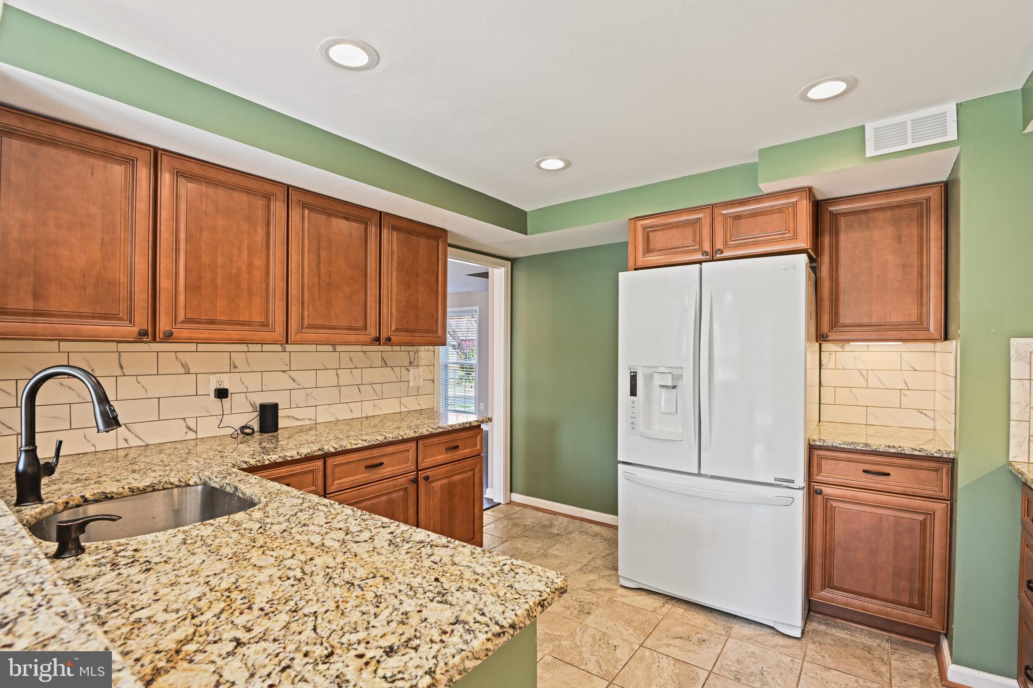 21174 Wildflower Square Ashburn, VA 20147 - Photo 8 of 30 a kitchen with stainless steel appliances kitchen island granite countertop a refrigerator and a sink