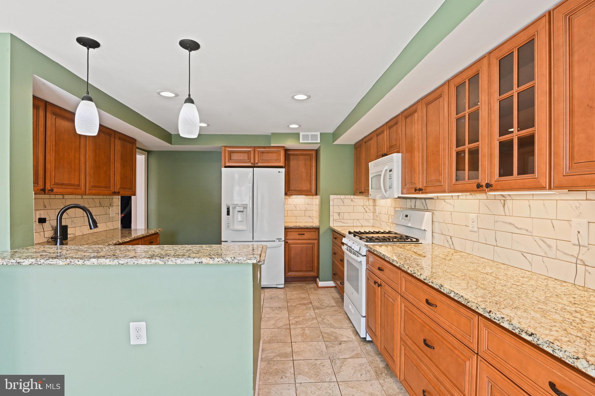21174 Wildflower Square Ashburn, VA 20147 - Photo 10 of 30 a large kitchen with granite countertop a sink and dishwasher a stove top oven with wooden floor