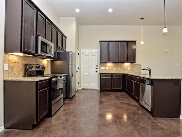 a kitchen with stainless steel appliances kitchen island granite countertop a sink a stove and a refrigerator
