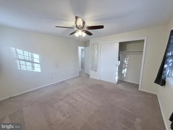 a view of a big room with a ceiling fan and a window