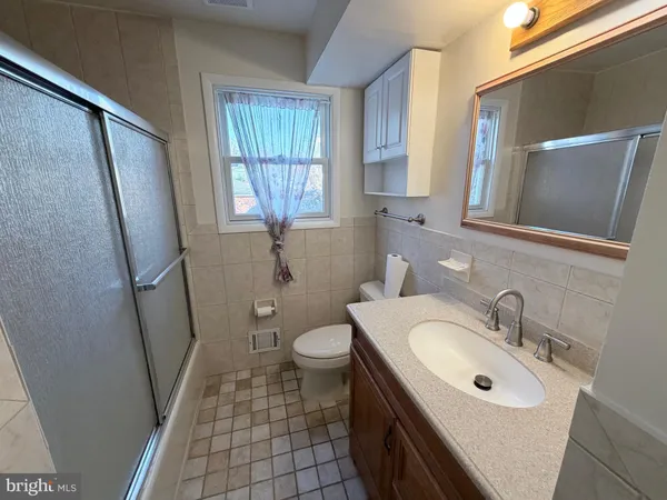 a bathroom with a sink a mirror a toilet and a window