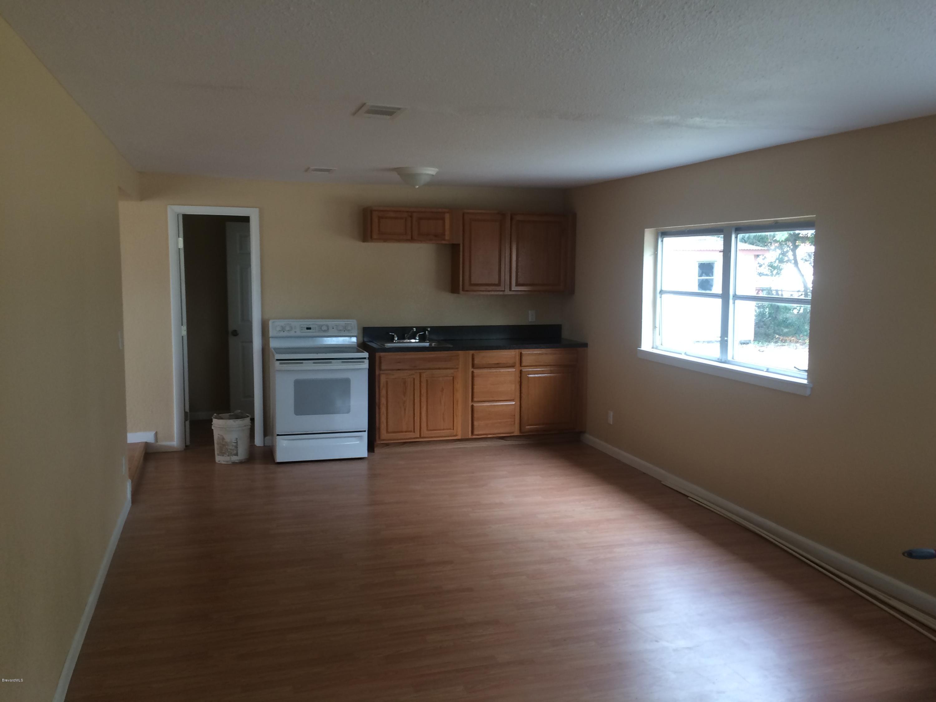 1040 Hickory Lane Cocoa, FL 32922 - Photo 5 of 17 an empty room with wooden floor kitchen view and windows