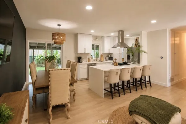 a dining hall with stainless steel appliances kitchen island granite countertop a dining table chairs and view living room